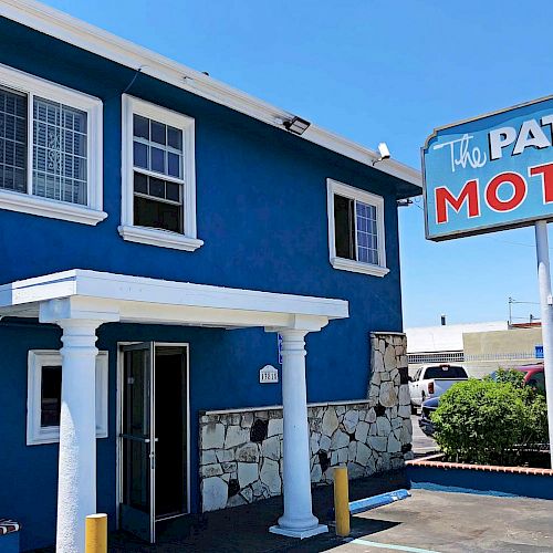 The image shows a two-story blue building with a sign reading 